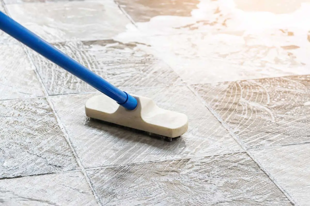 Cleaning the tile floor with floor scrubber brush and water